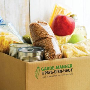 Donation box with various food. Open cardboard box with butter, canned goods, cereals and fruits.